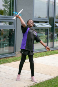 Student launching a paper plane outside the classroom